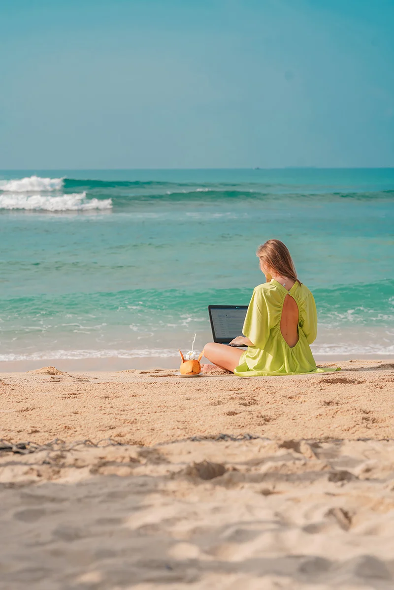 A traveler working on a laptop beside the beach